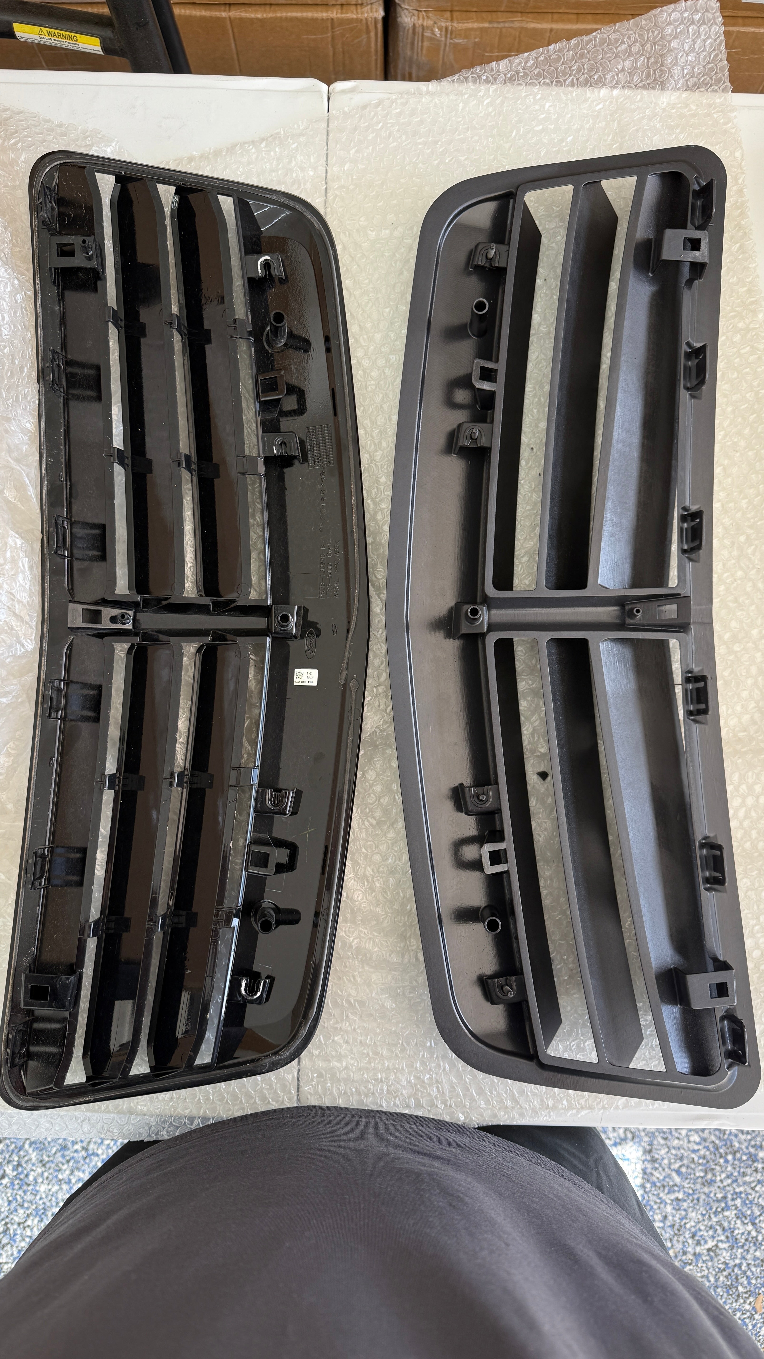 Two black car grille components on a white surface