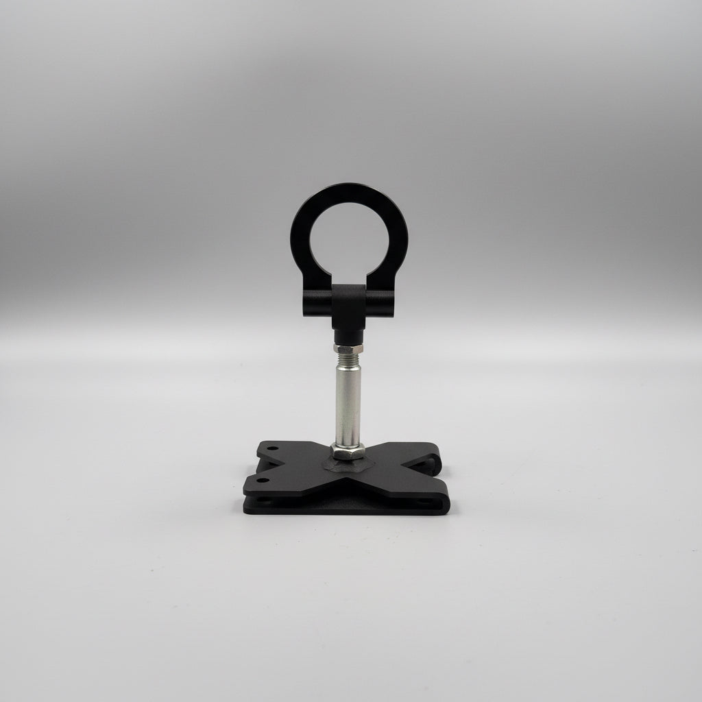 A black metal stand with a circular top loop and a square base, shown on a white tabletop with shipping boxes partially visible in the background.